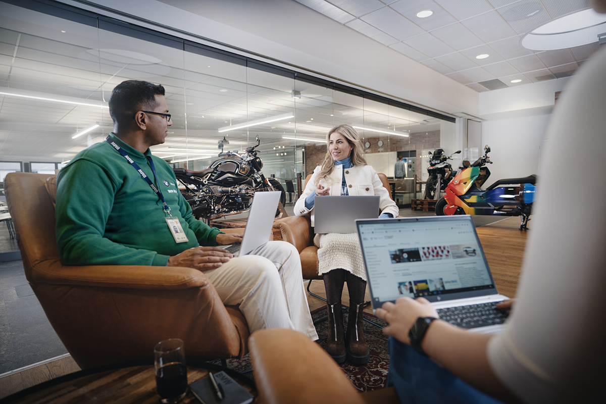 Two employees sitting in an armchair in a BMW Motorrad showroom, having a discussion.