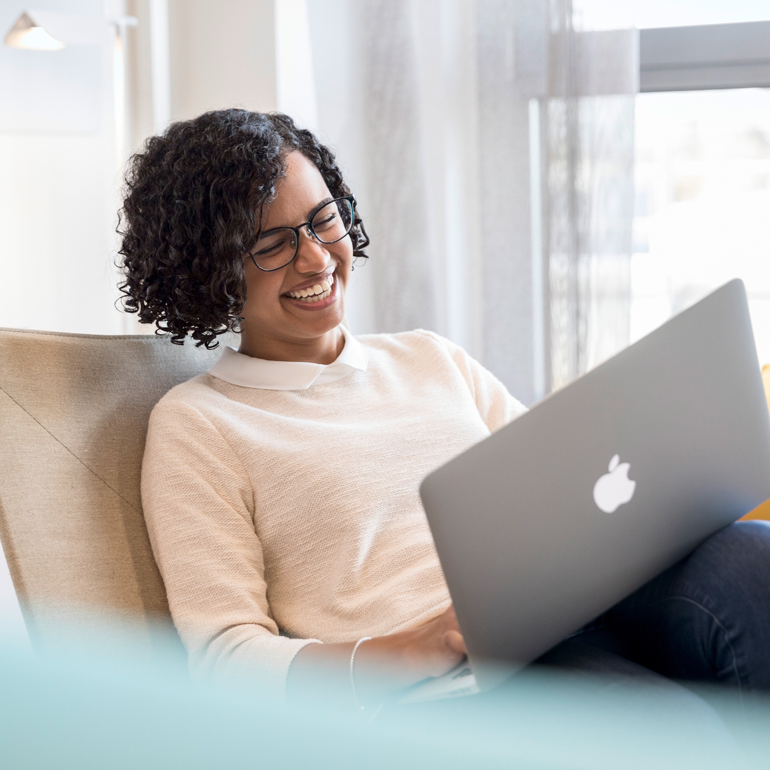 A woman at work laughing at her laptop.