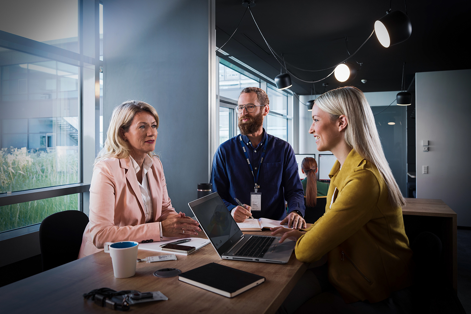 Three employees at the BMW Group are having a conversation.