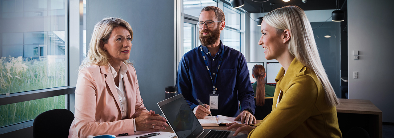 Three BMW professionals, two women and a man, are having a conversation.