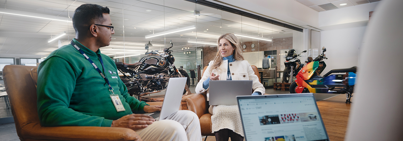 Three BMW employees are working together their a laptop and having a exchange.