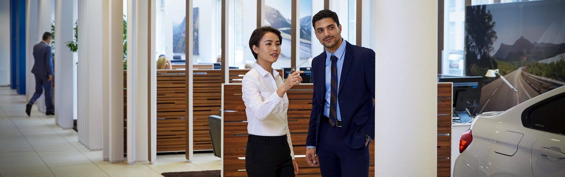 Two professional car salespersons having a conversation in a BMW dealership.