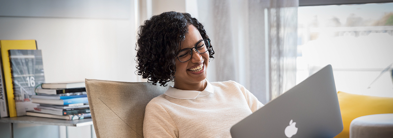 A woman using her laptop, laughing.
