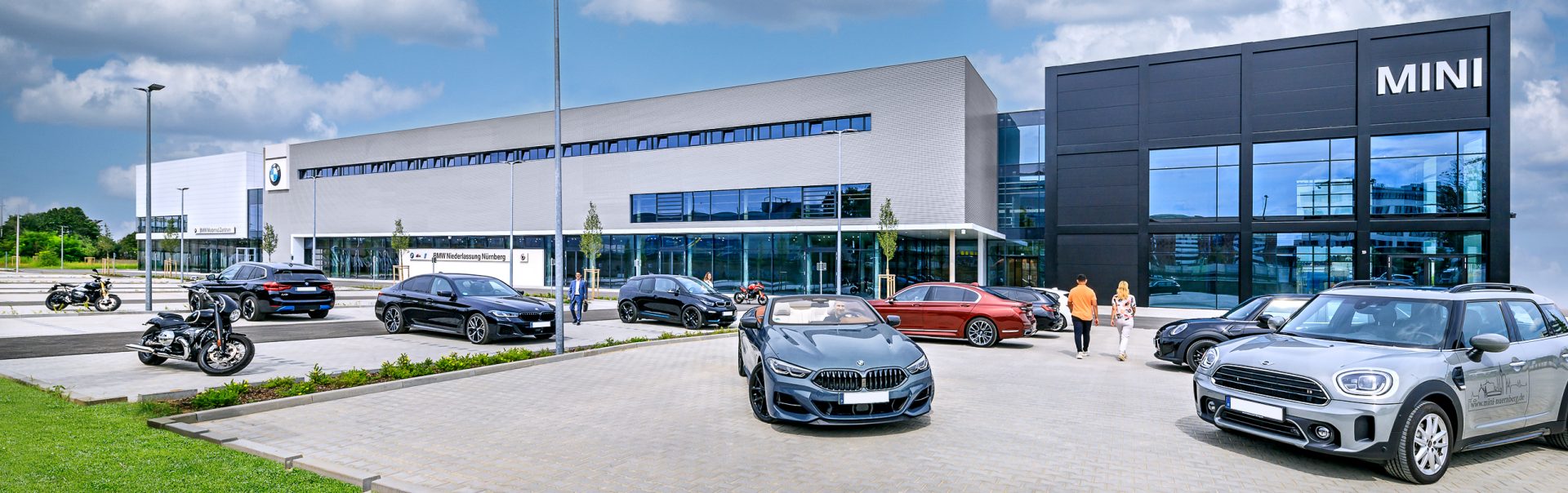 Exterior view of the BMW and MINI dealership in Nuremberg, with several vehicles parked in front.