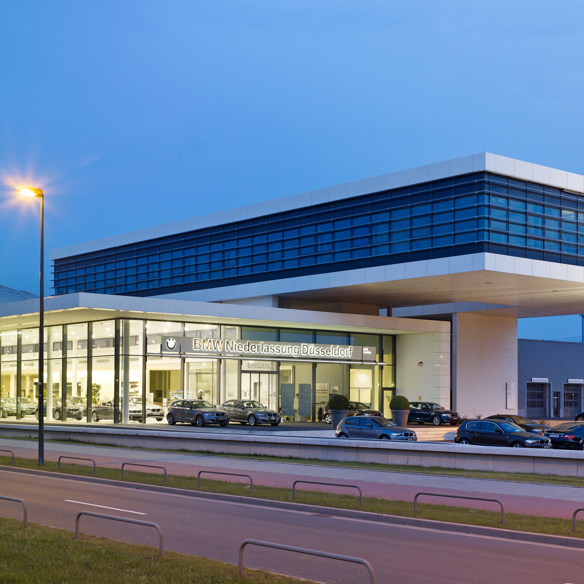 Exterior view of the BMW retail centre in Düsseldorf at night, showcasing modern architecture.