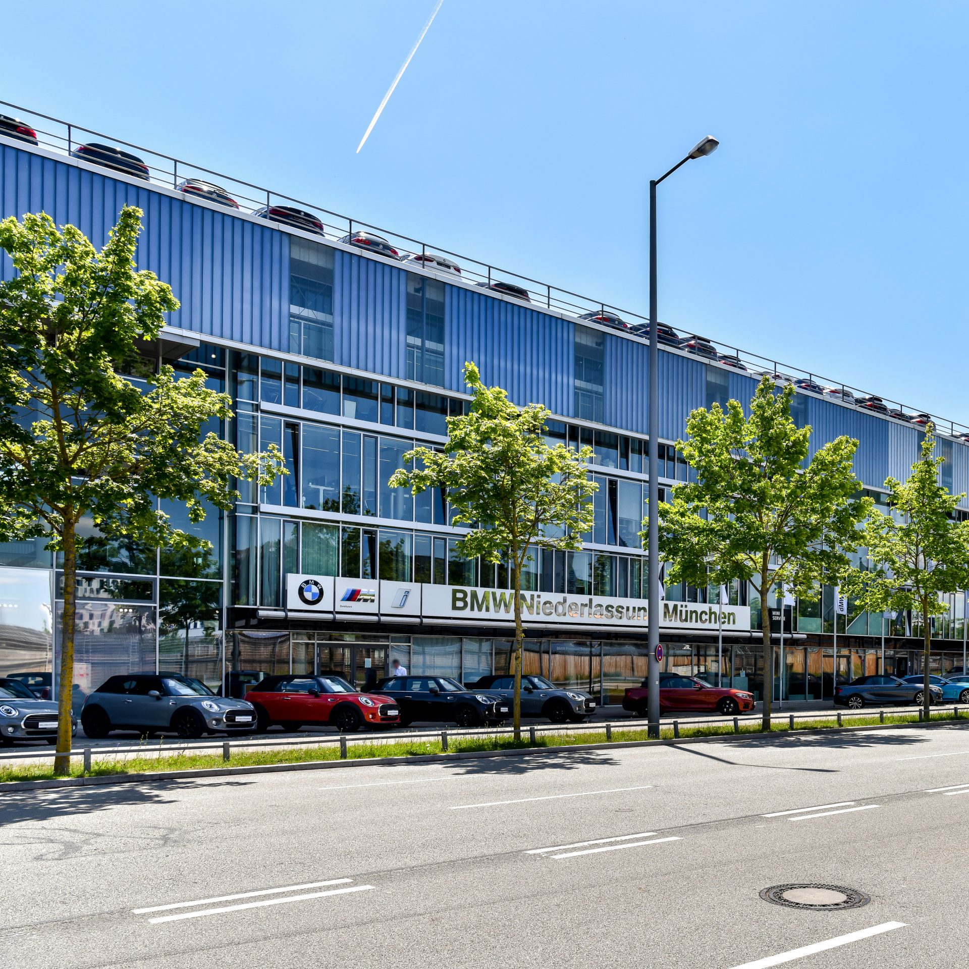 Exterior view of the BMW dealership in Munich with various cars parked outside.