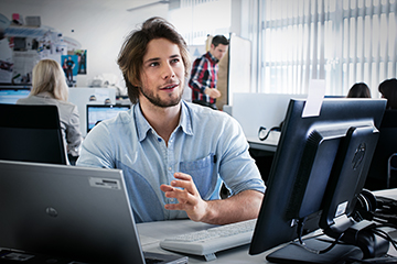 Thoughtful apprentice as an e-commerce merchant at the BMW Group in an office with computers in the background.