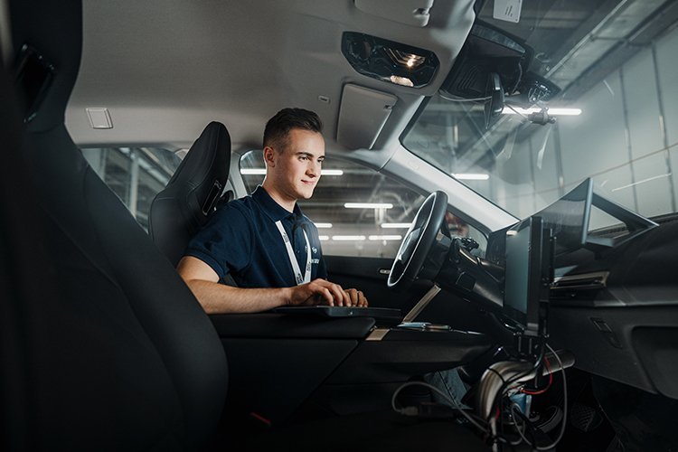 A focused BMW automotive engineer working inside a modern vehicle cabin, showcasing advanced technology.