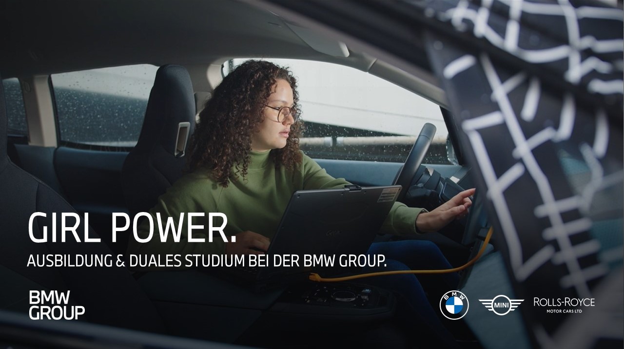 A young woman working on a laptop inside a BMW vehicle, showcasing women empowerment and education.