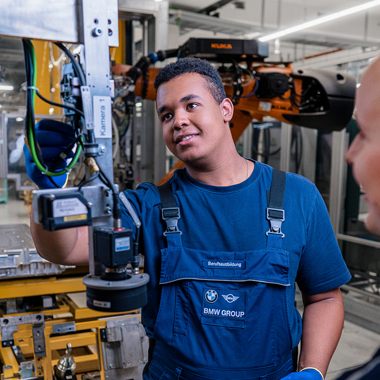Hands-on training in BMW automotive manufacturing with an apprentice and advanced technology.