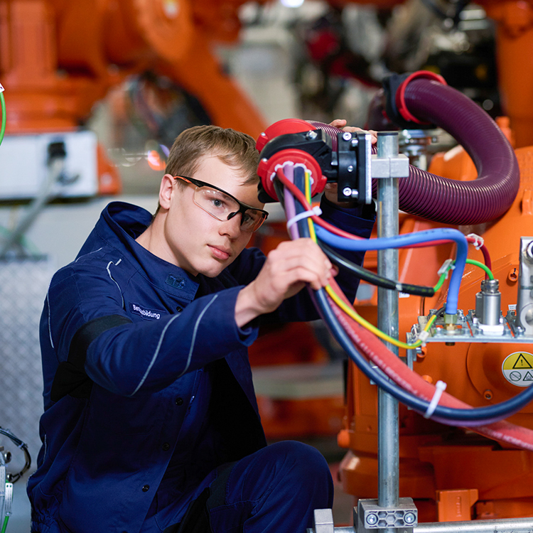 A trainee at the BMW Group works on robots