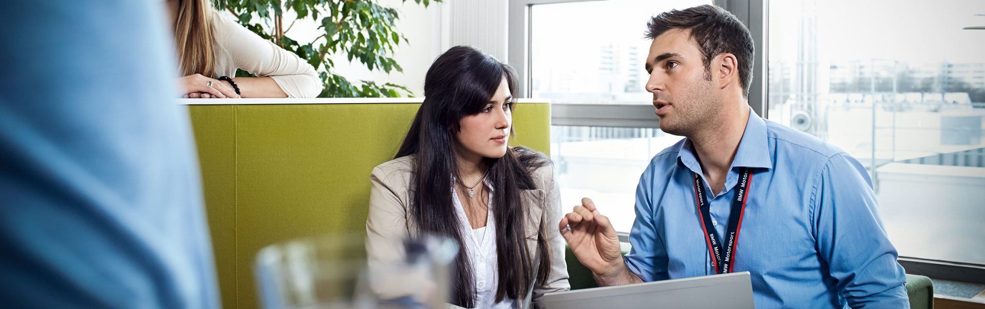 Two industrial clerks engaged in a collaborative meeting in a bright office environment at the BMW Group.