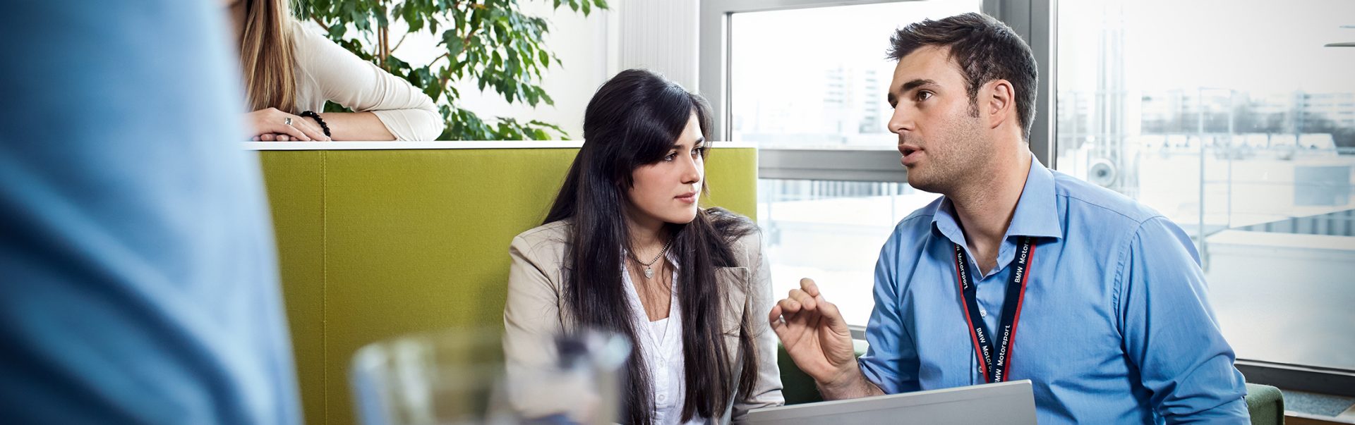 Business discussion between two insurance and finance trainees at the BMW Group in a bright office.