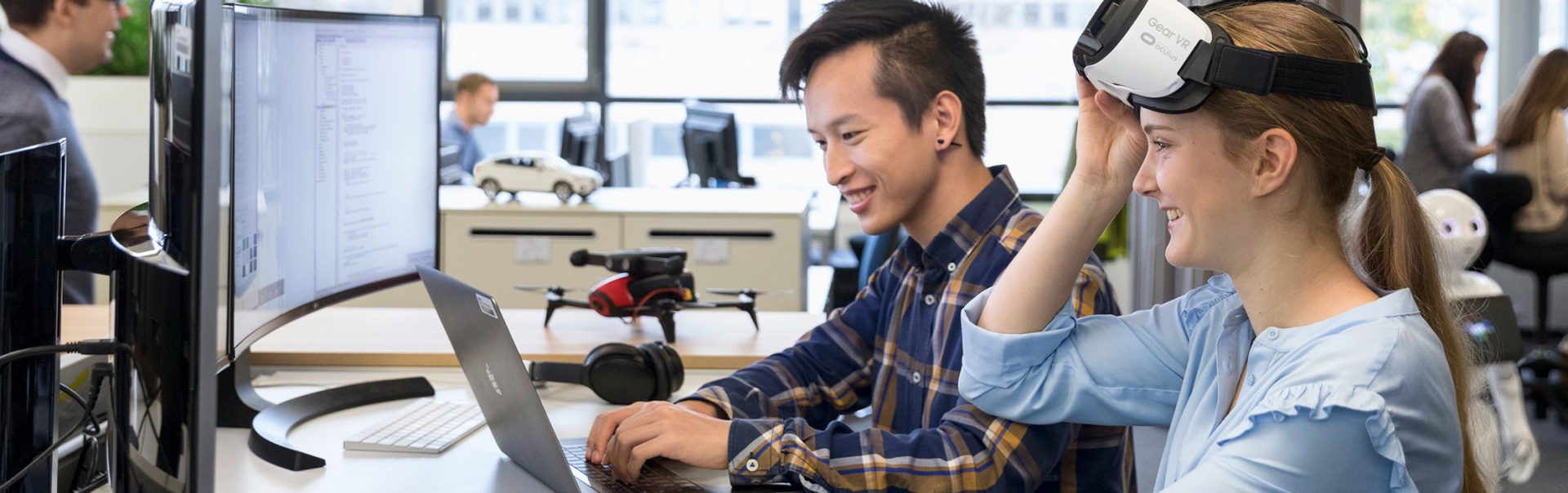 Two apprentices as IT specialists for systems integration engaging with virtual reality technology in a modern workspace at the BMW Group.