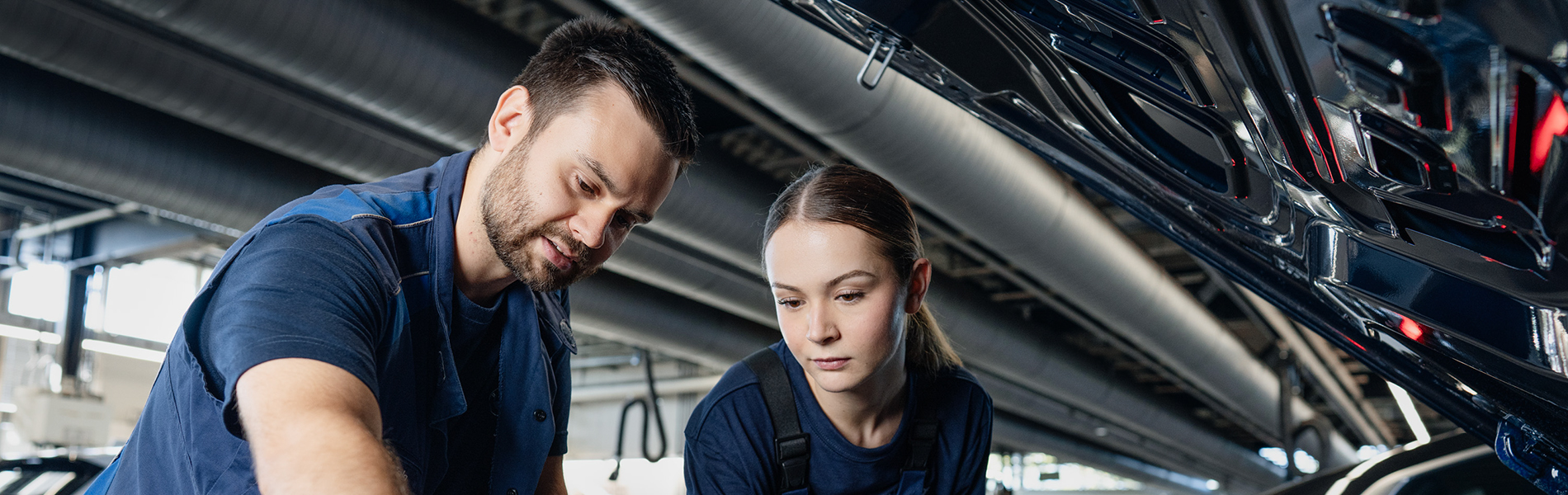 Two trainees are working on an engine in a BMW workshop.