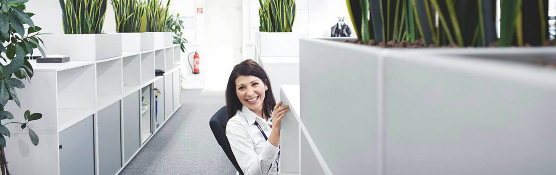Smiling trainee marketing communications specialist at the BMW Group in a modern office with plants.