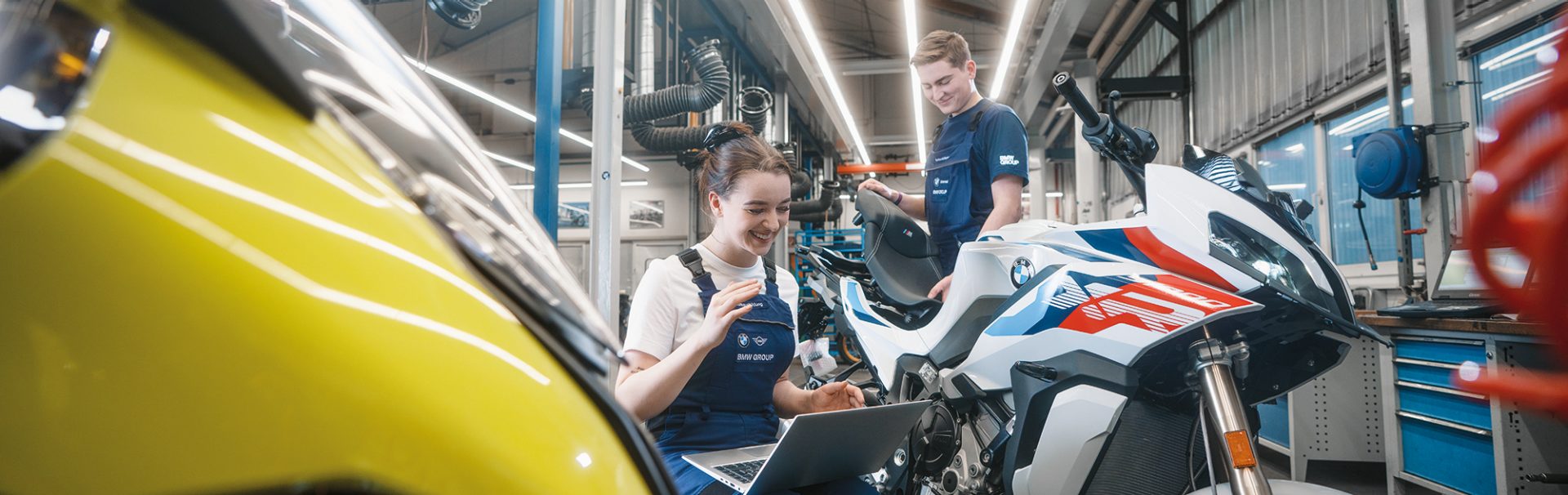 Two-wheeler mechatronics technicians work on a BMW motorcycle in the workshop.