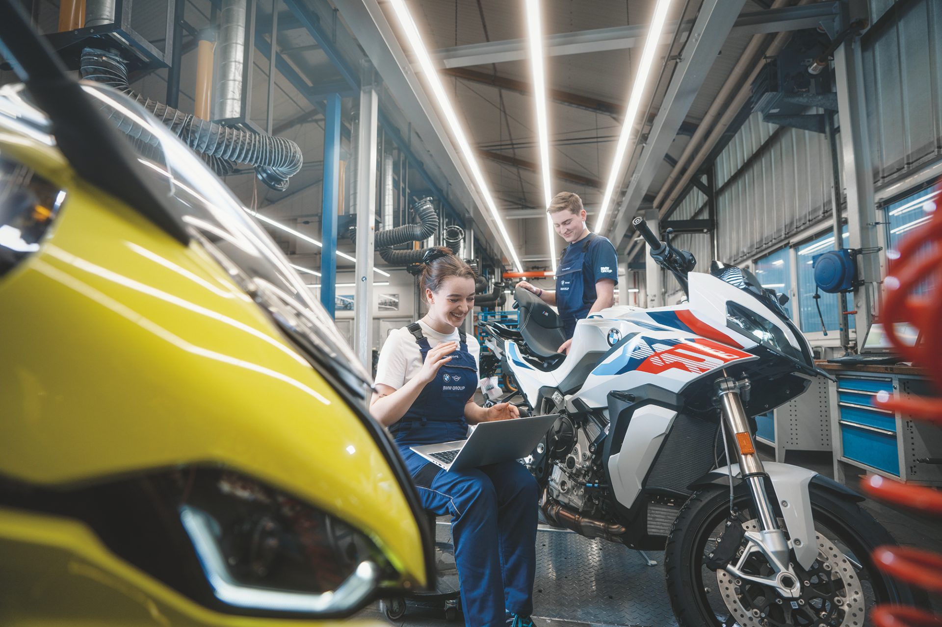 Two-wheeler mechatronics technicians work on a BMW motorcycle in the workshop.
