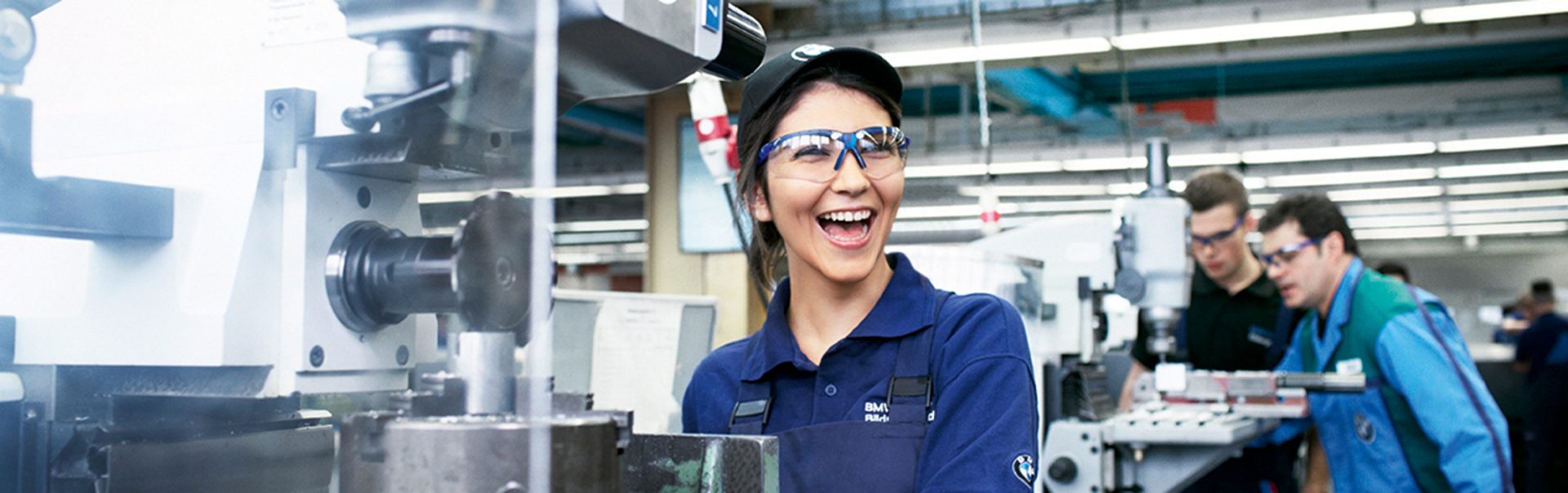 Apprentice mechatronics technician at the BMW Group at her workplace with machines in a production environment.