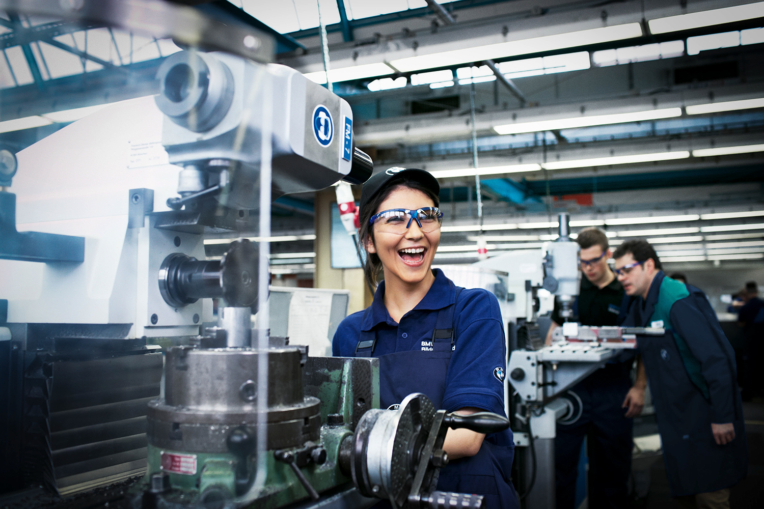 Apprentice mechatronics technician at the BMW Group at her workplace with machines in a production environment.