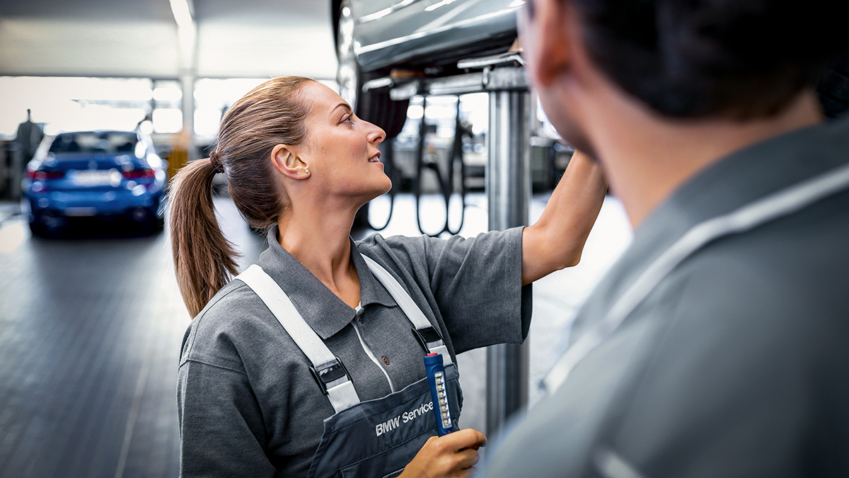 An apprentice for bodywork maintenance technology at the BMW Group carries out a bodywork inspection on a vehicle.
