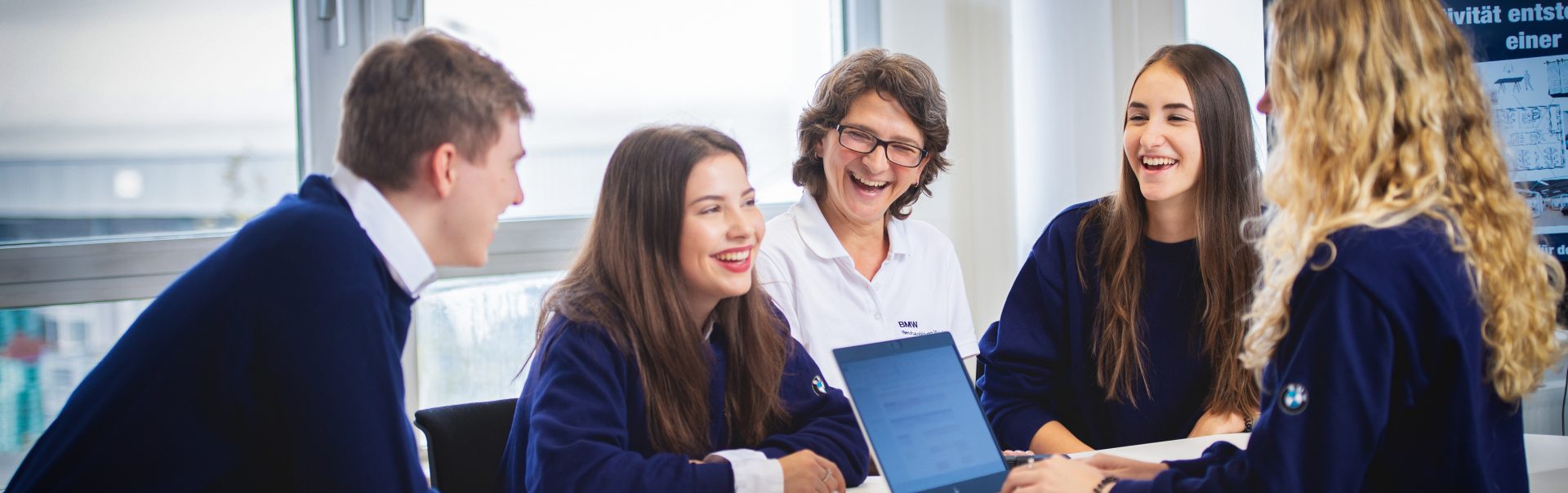Smiling employees in management and project assistance at the BMW Group discuss a project in a conference room.