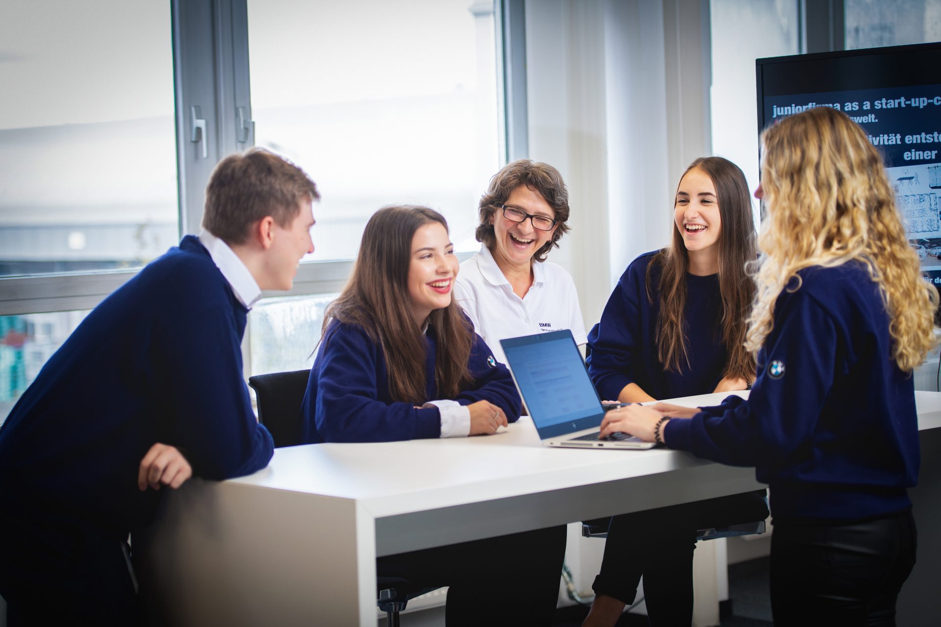 Smiling employees in management and project assistance at the BMW Group discuss a project in a conference room.