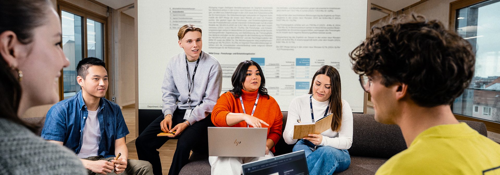 Smiling employees in management and project assistance at the BMW Group discuss a project in a conference room.
