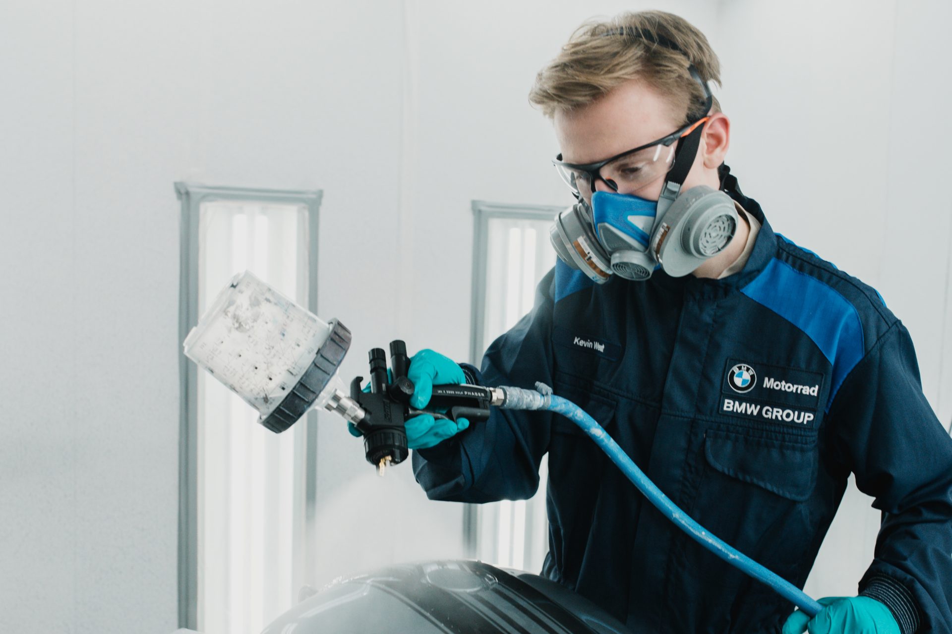 An apprentice process mechanic for painting technology at the BMW Group during the painting process of a motorcycle part.