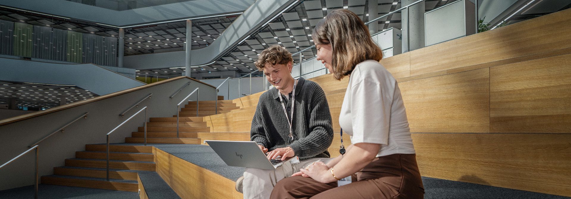 Two smiling trainees as social security clerks at the BMW Group in a friendly working environment.
