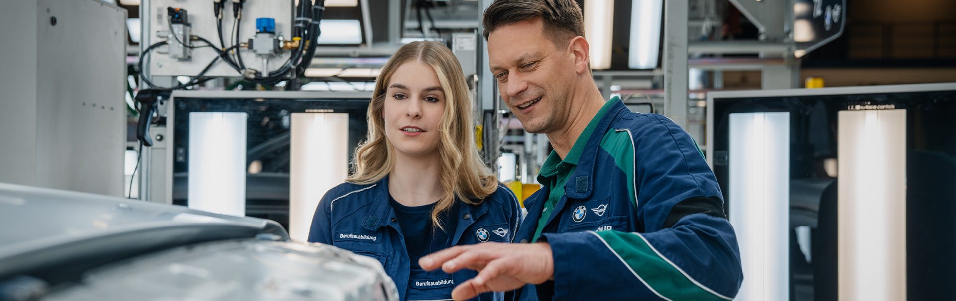 Technical training at the BMW Group, employee explains the production process to a trainee.