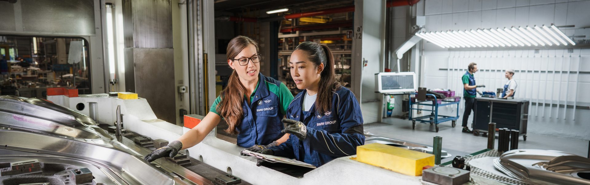Two BMW Group tool mechanics at work on a machine component.