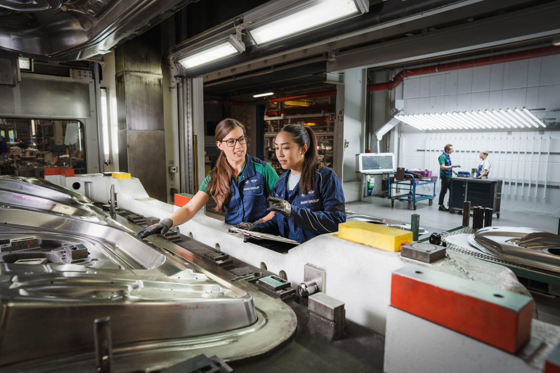 Two BMW Group tool mechanics at work on a machine component.