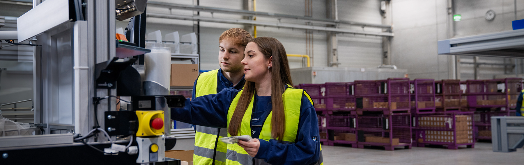 Two trainees are working on a machine in a BMW warehouse.