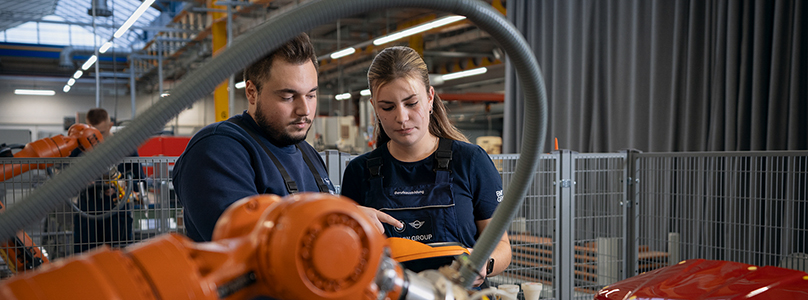 Two work-study students studying Electrical and Information Technology are working together on a robot in the workshop.