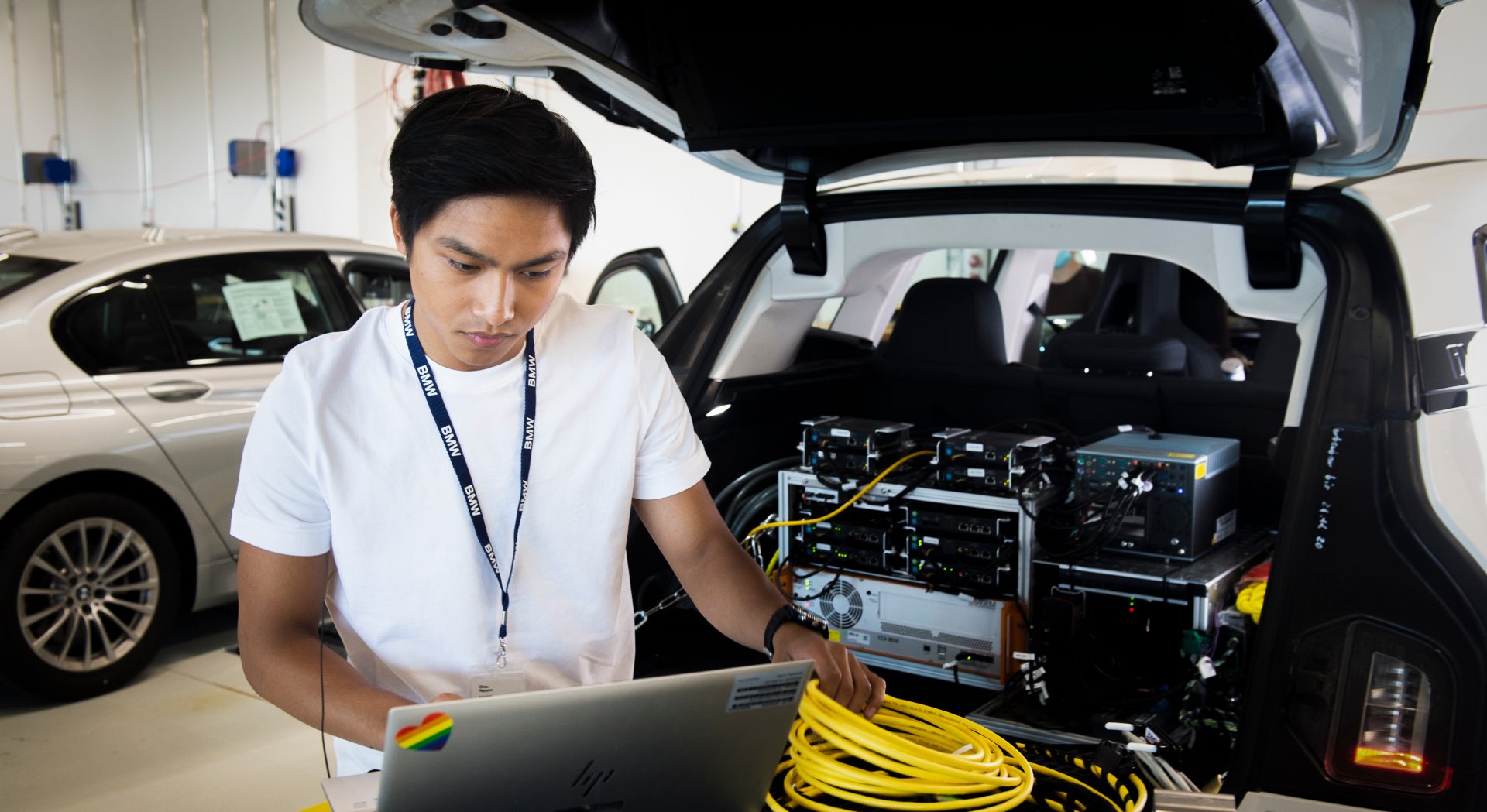 Dual computer science student works on his laptop on a BMW.