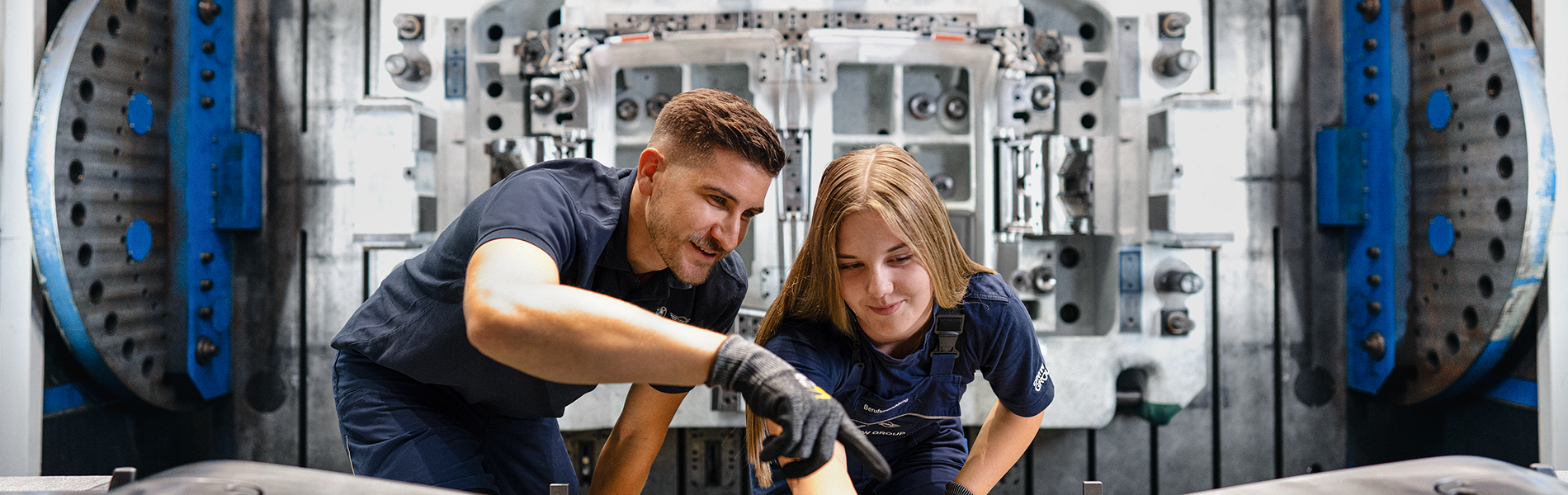 A dual student in design at the BMW Group working on a vehicle body and chats with her trainer.