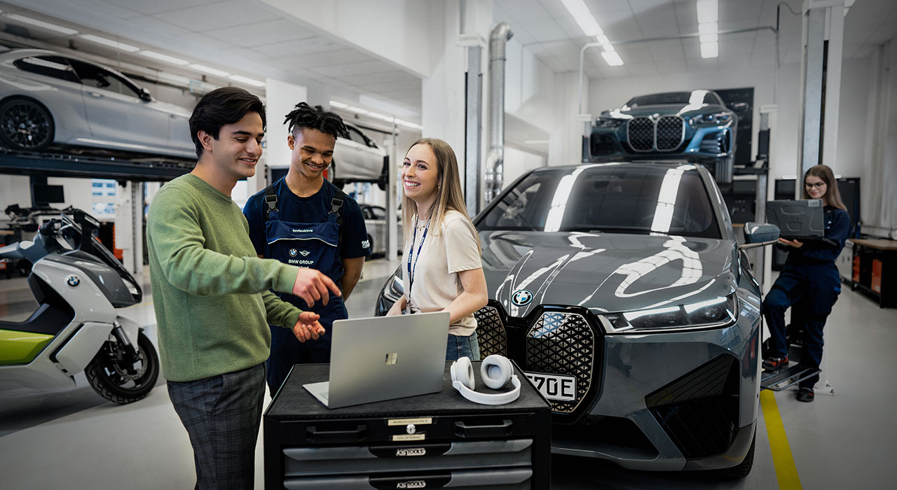 The photo shows three apprentices in a BMW work shop.