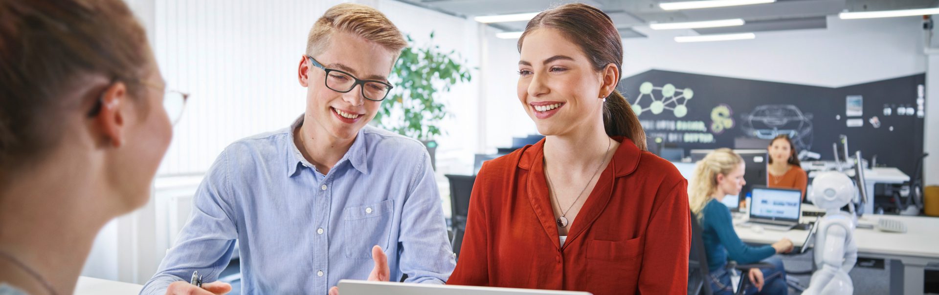 Two young professionals engaged in a collaborative meeting in a modern office environment at the BMW Group.
