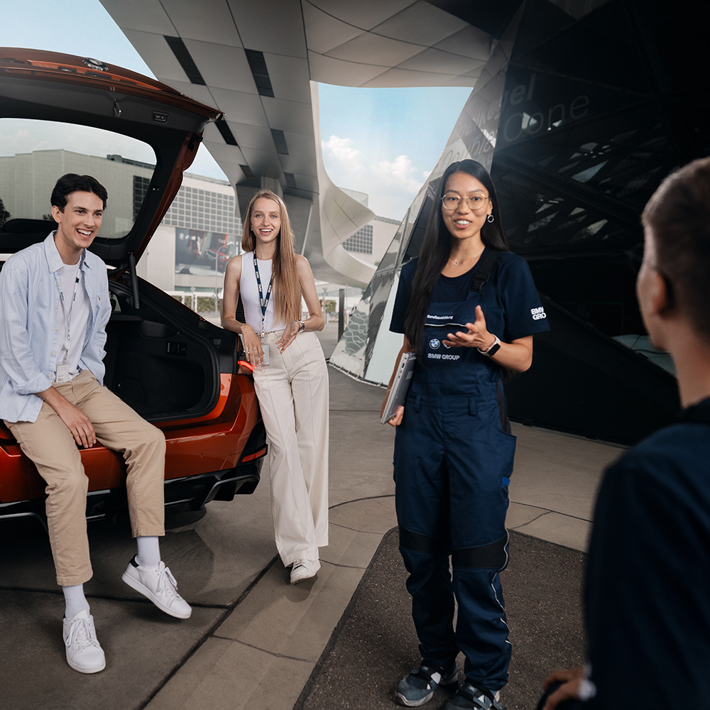 Three dual students are having a conversation outside the BMW world.