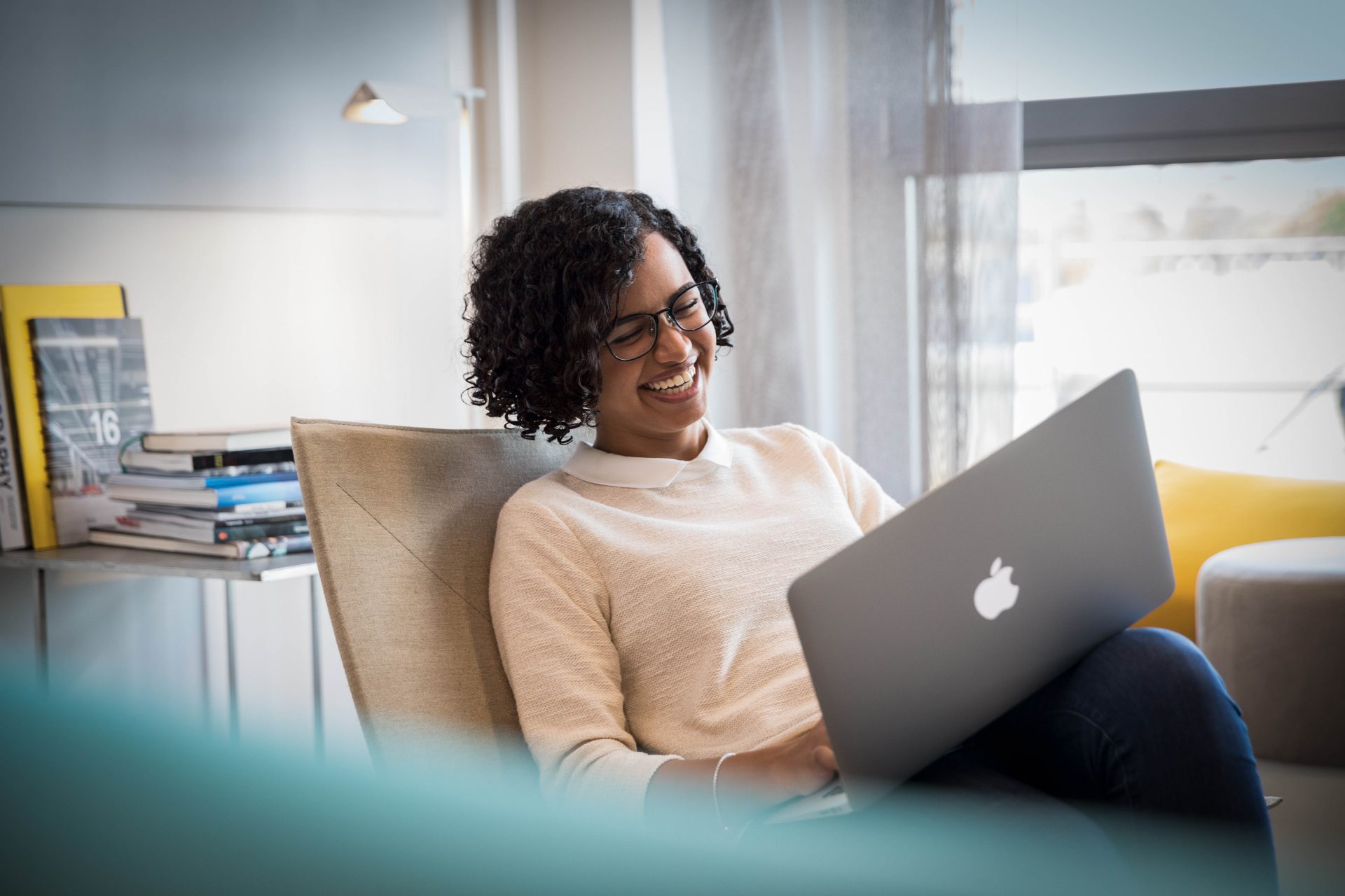 A woman laughing while using a laptop in a modern living space.