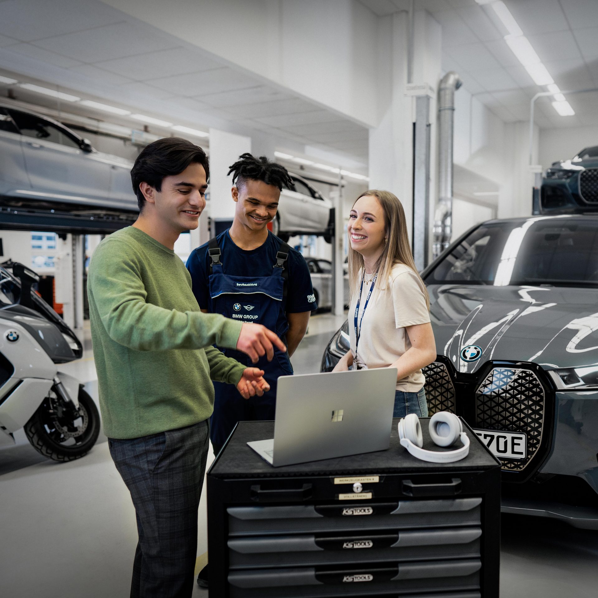 The picture shows three apprentices at work in a BMW workshop.