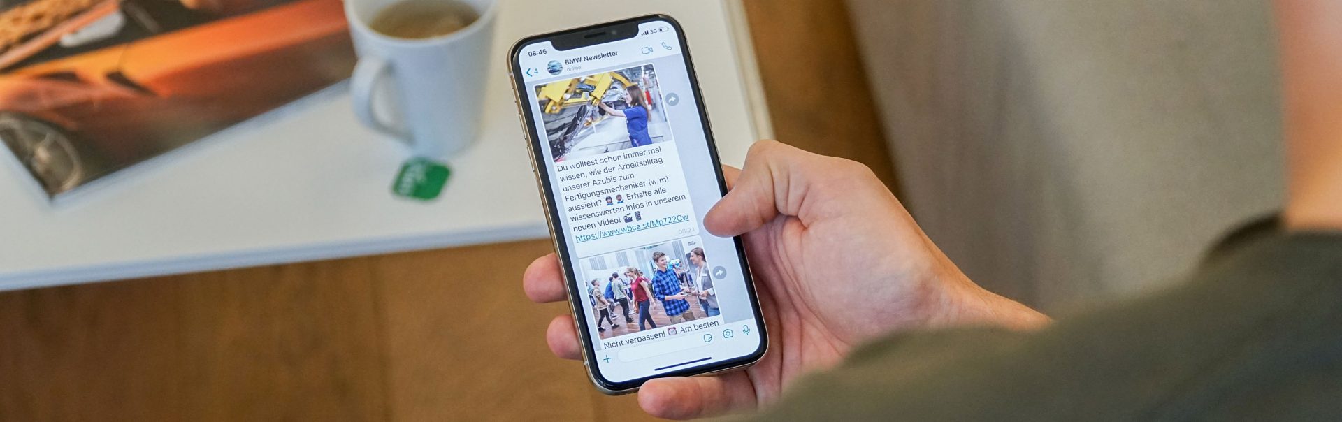  A hand holding a smartphone with the screen showing an open BMW Pupil newsletter.
