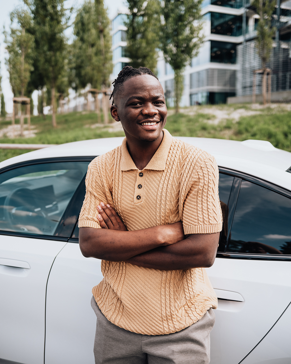Student leaning against a white BMW i5.