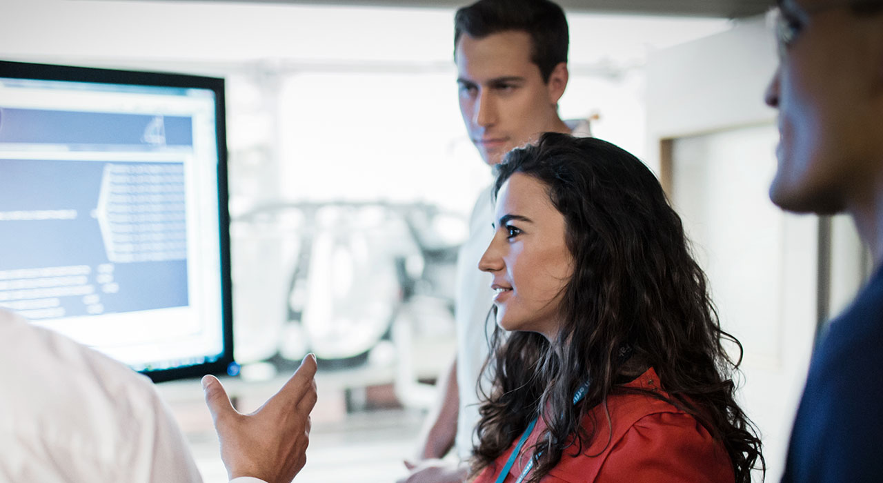 Four BMW professionals, having a discussion about a diagramm shown on the computer screen.