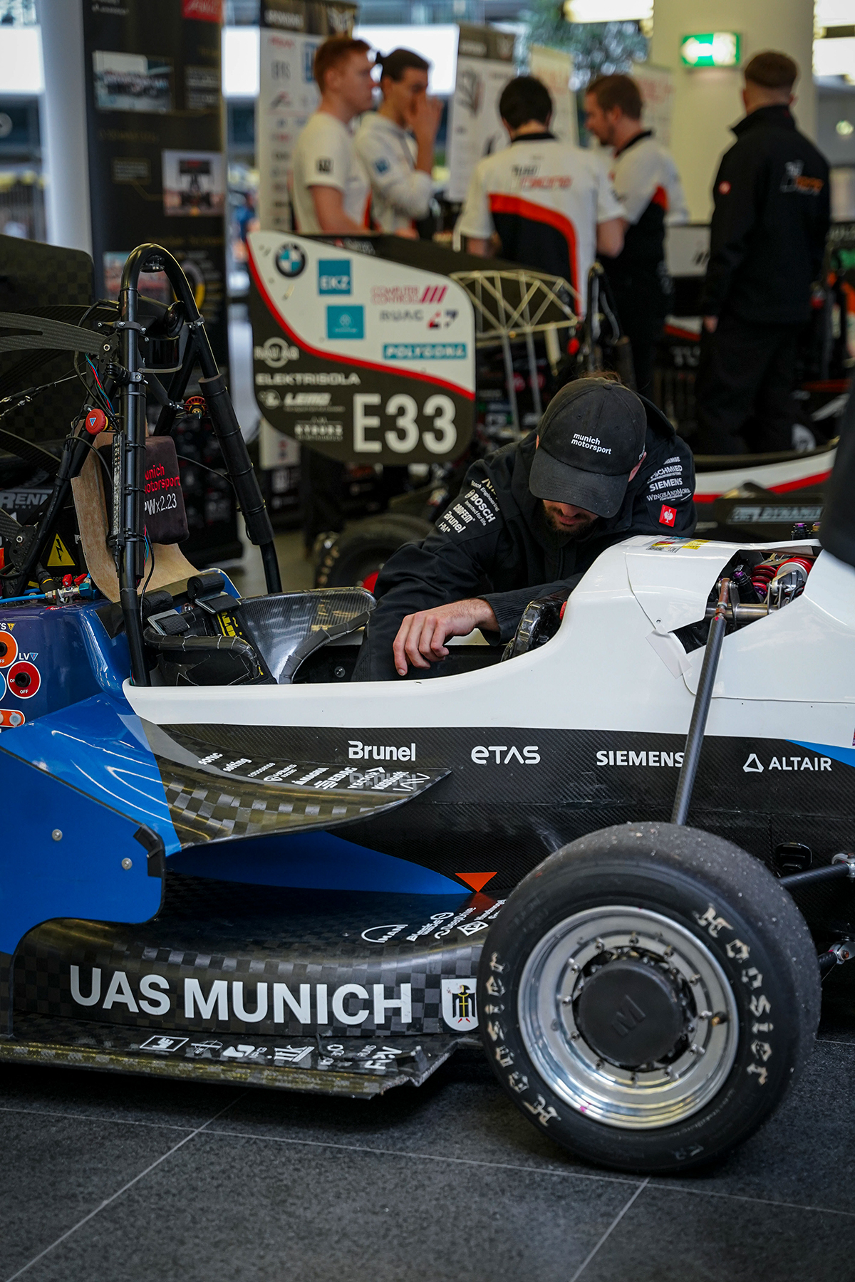 A technician working on a Formula Student racing car in a workshop.