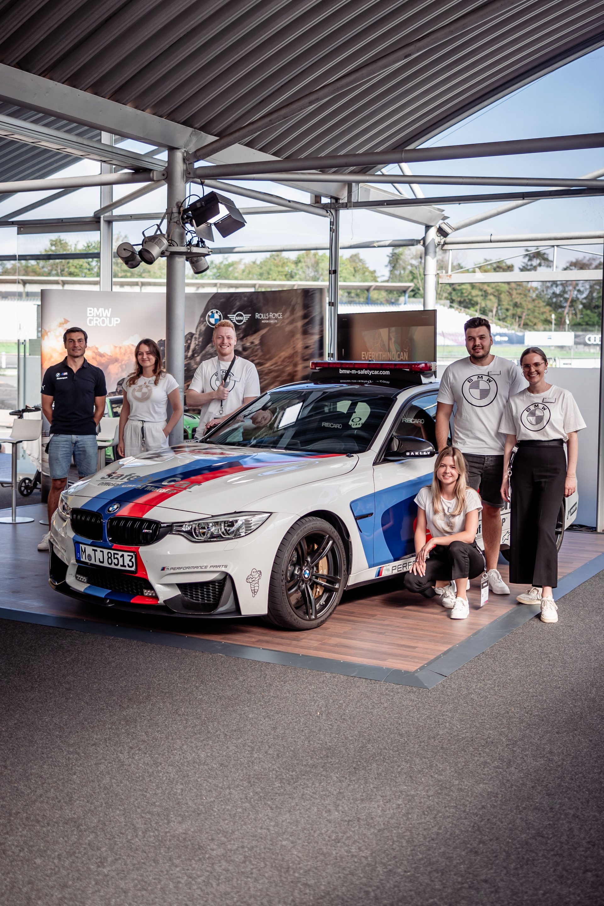 BMW Group team standing next to a BMW M3.