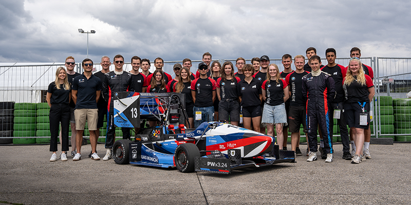 Formula Student Team municHMotorsport mit BMW Team hinter ihrem Rennwagen.