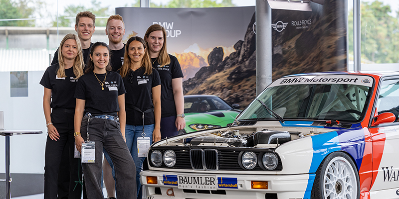 BMW Team beim Motorsport-Event mit legendärem Fahrzeug.