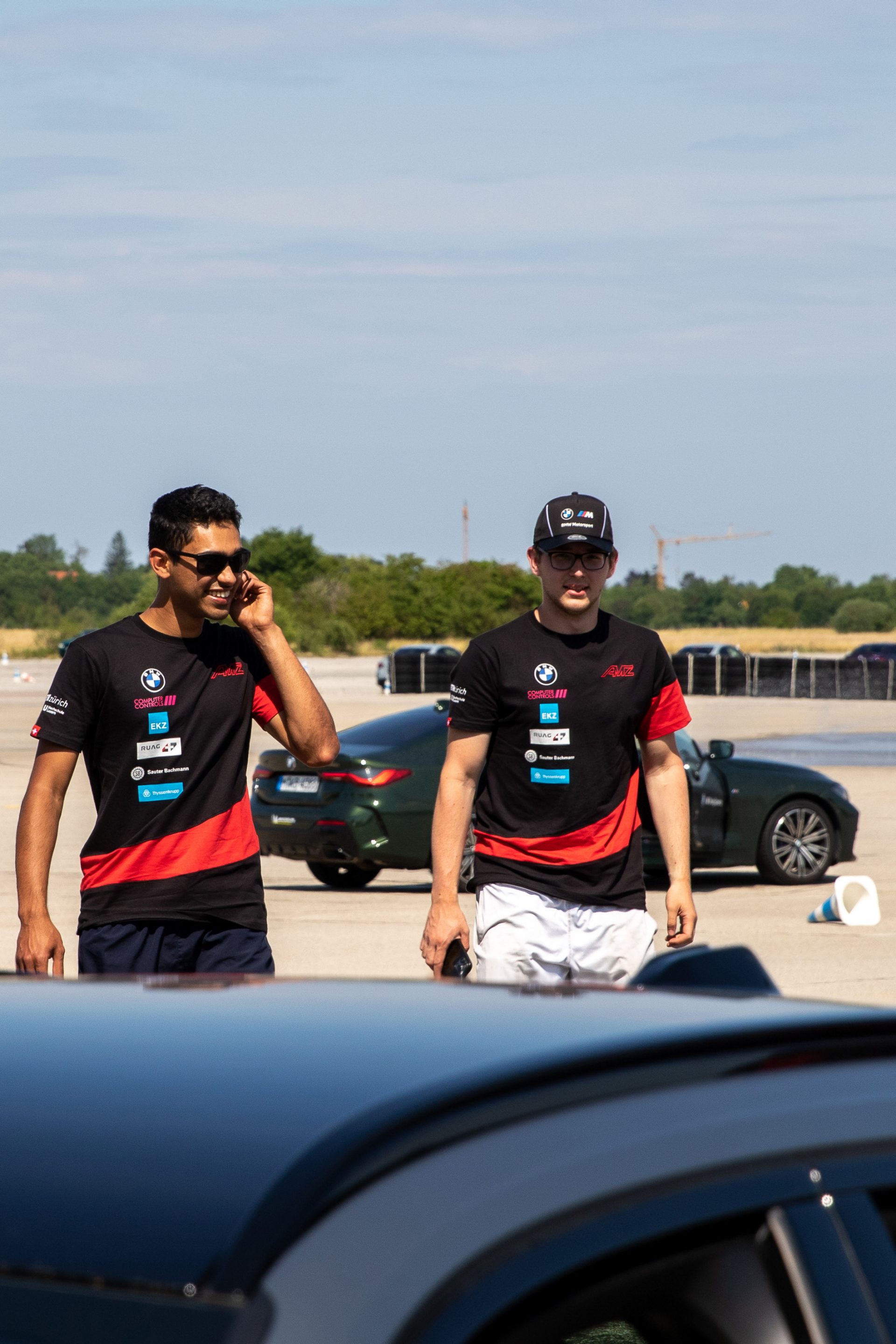 Two young men on a test track with two BMW Cars.